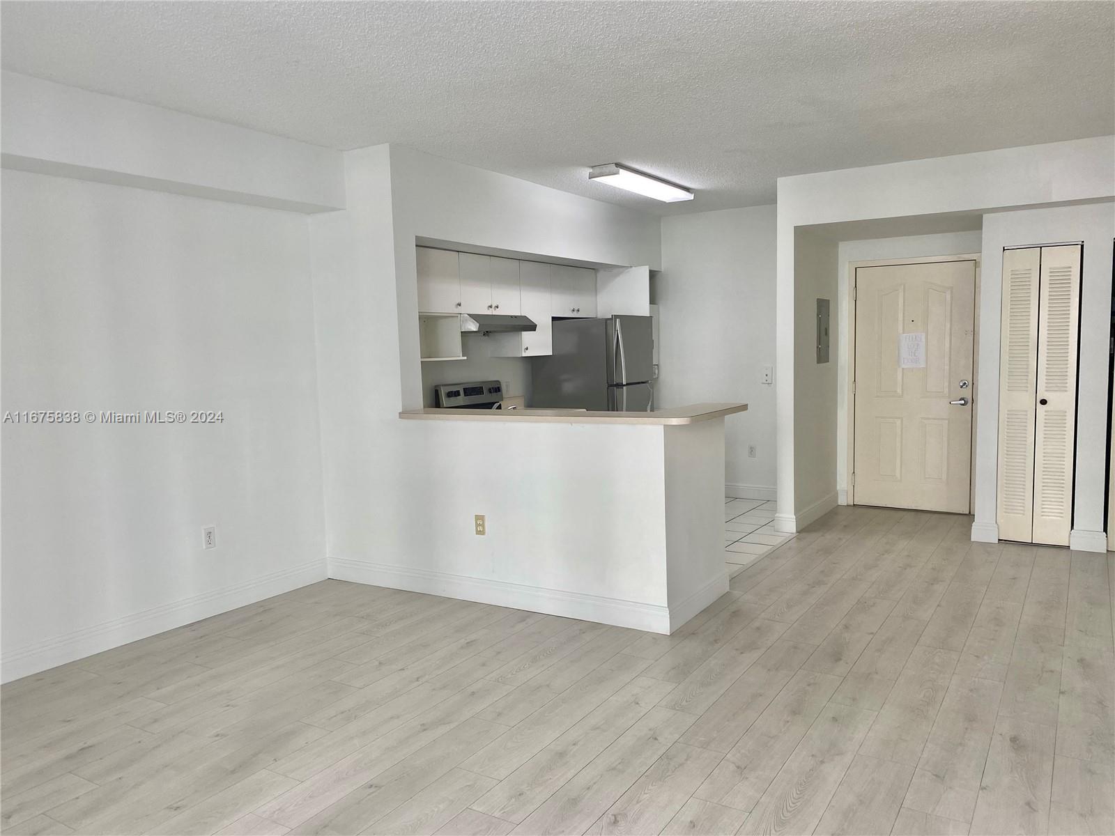 a view of a kitchen with wooden floor and white cabinets