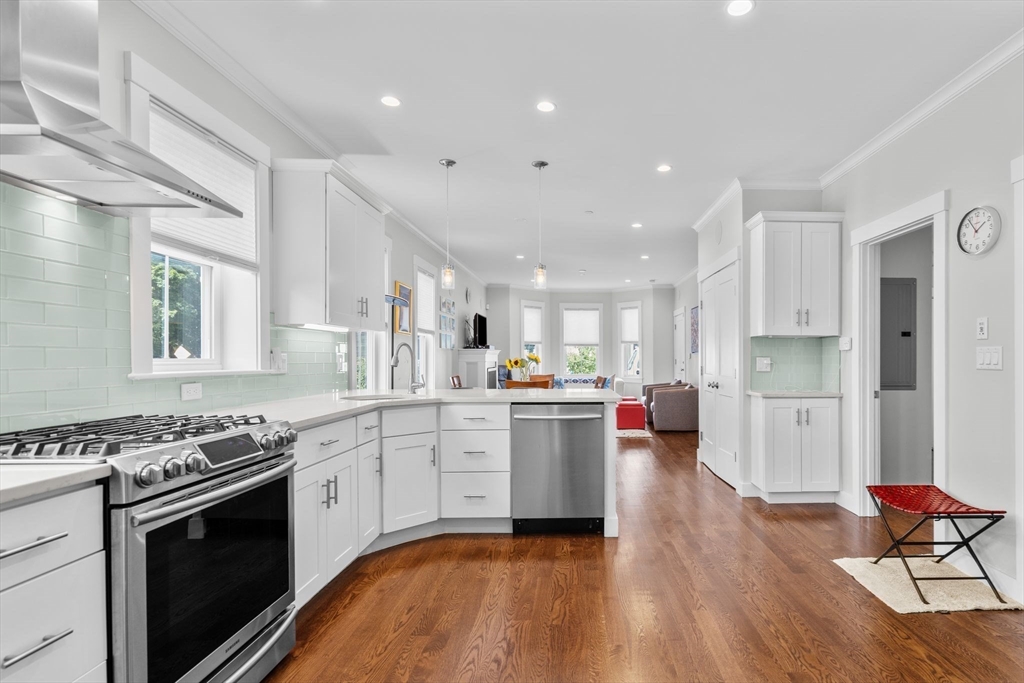 a kitchen with stainless steel appliances granite countertop wooden floors and white cabinets