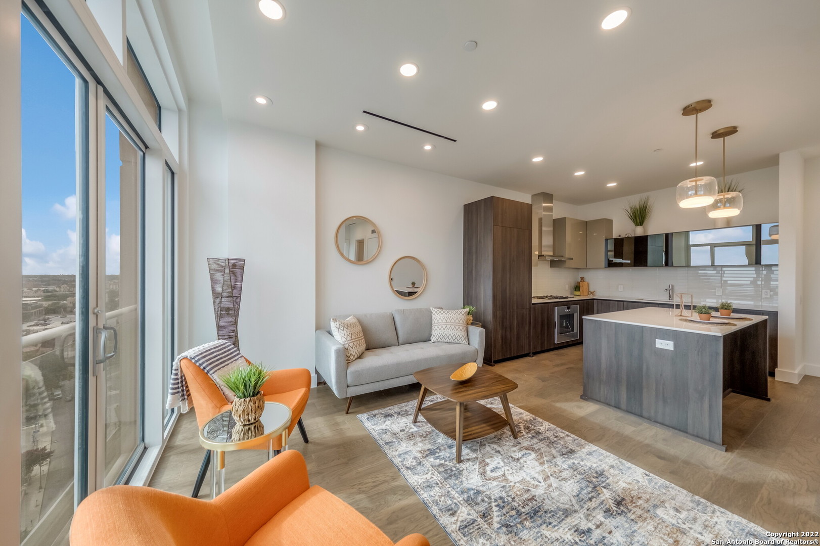 a living room with stainless steel appliances kitchen island granite countertop furniture a rug kitchen view and a chandelier