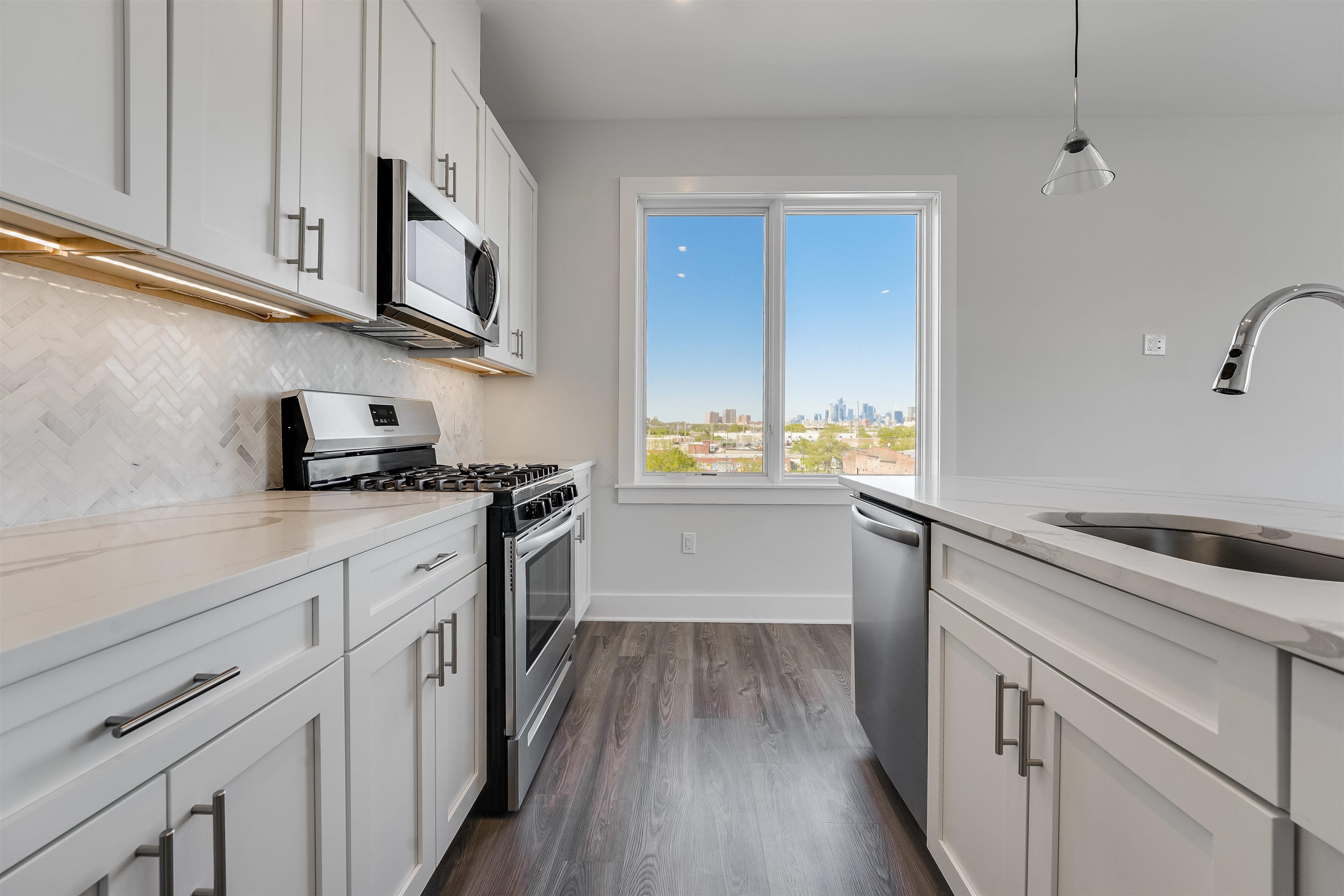 a kitchen with stainless steel appliances white cabinets sink and wooden floor