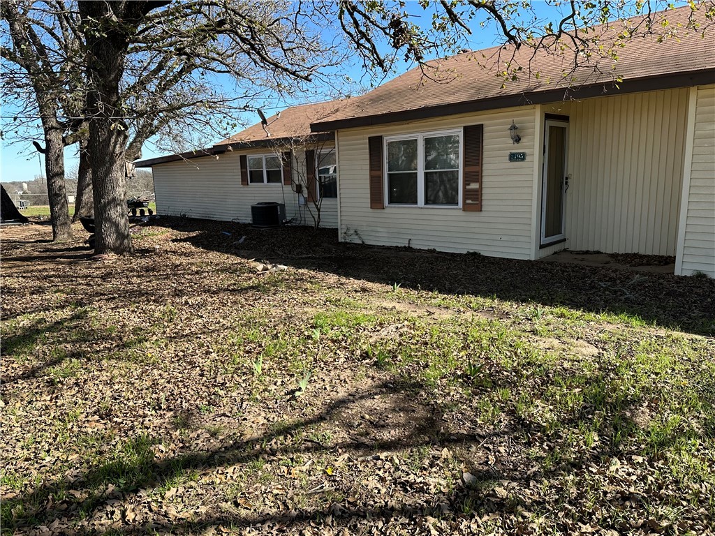 Back of house with a lawn and central air conditio