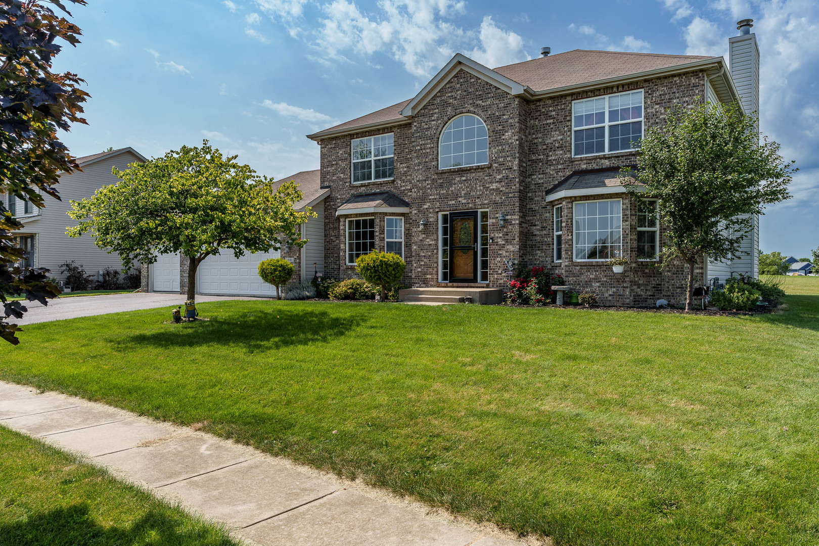 a front view of a house with a yard and trees