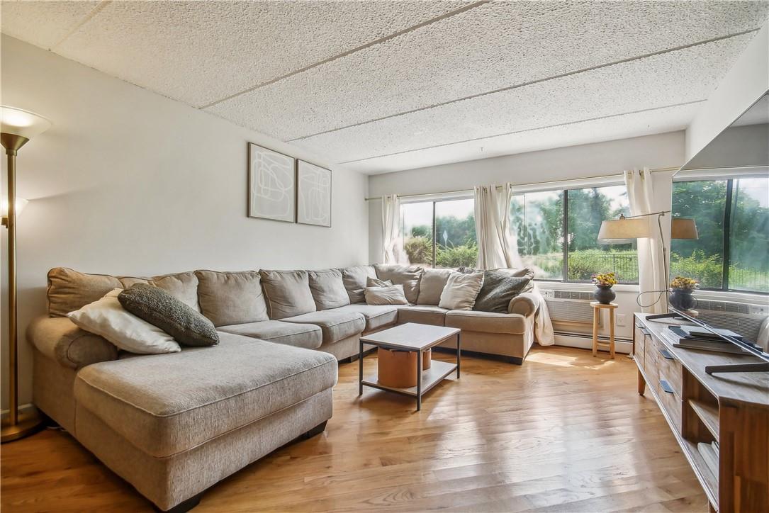 Living room featuring light hardwood / wood-style floors, a baseboard heating unit, a textured ceiling, and a wall unit AC