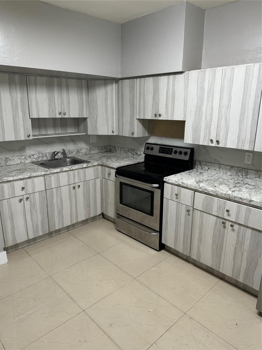 a kitchen with granite countertop a stove sink and cabinets