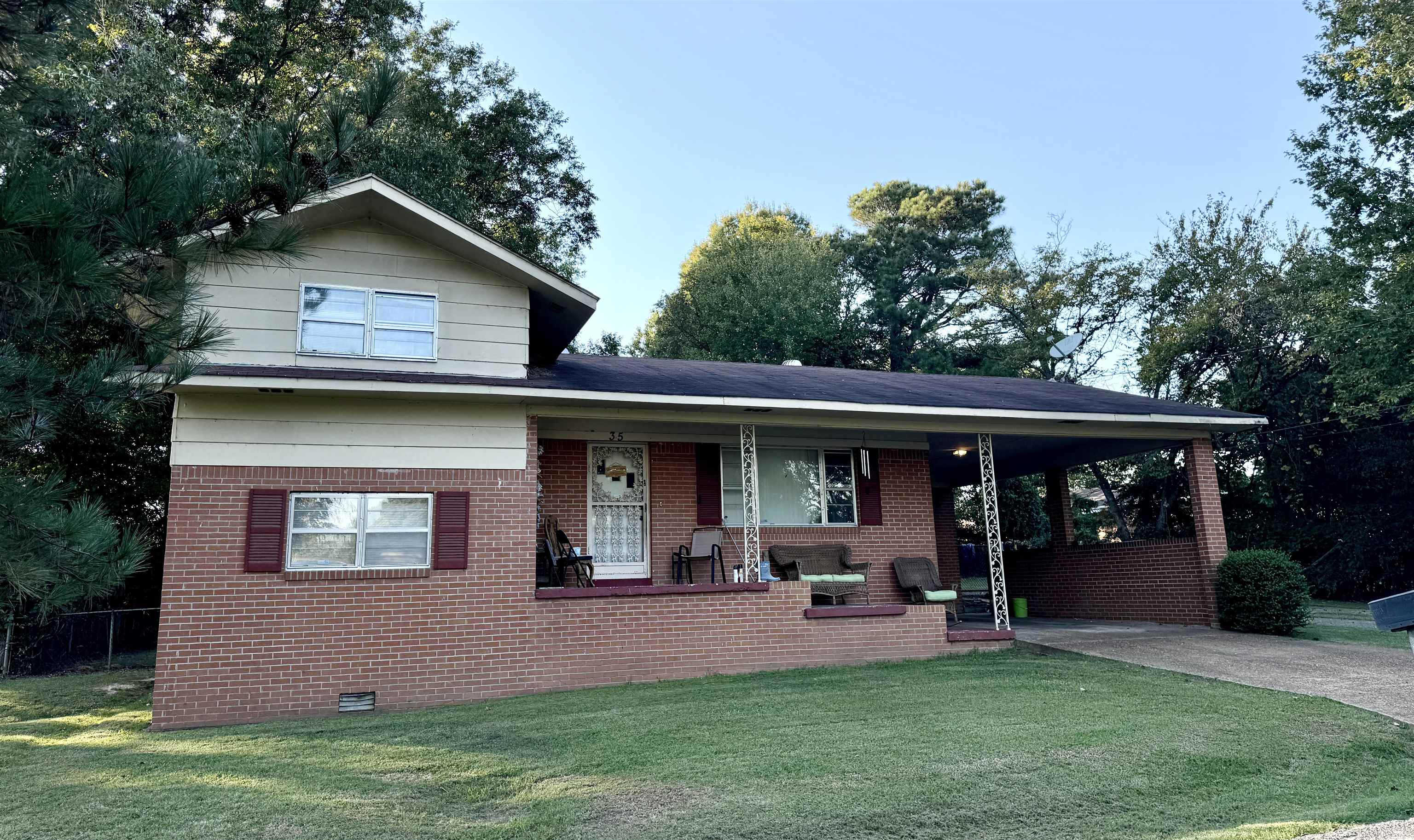 View of front of house with a porch, a front lawn, and a carport