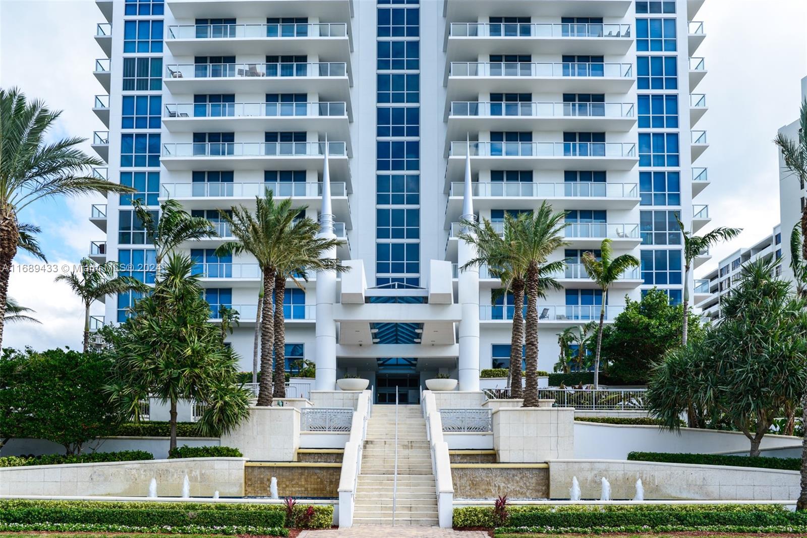 a front view of multi story residential apartment building with yard and parking space