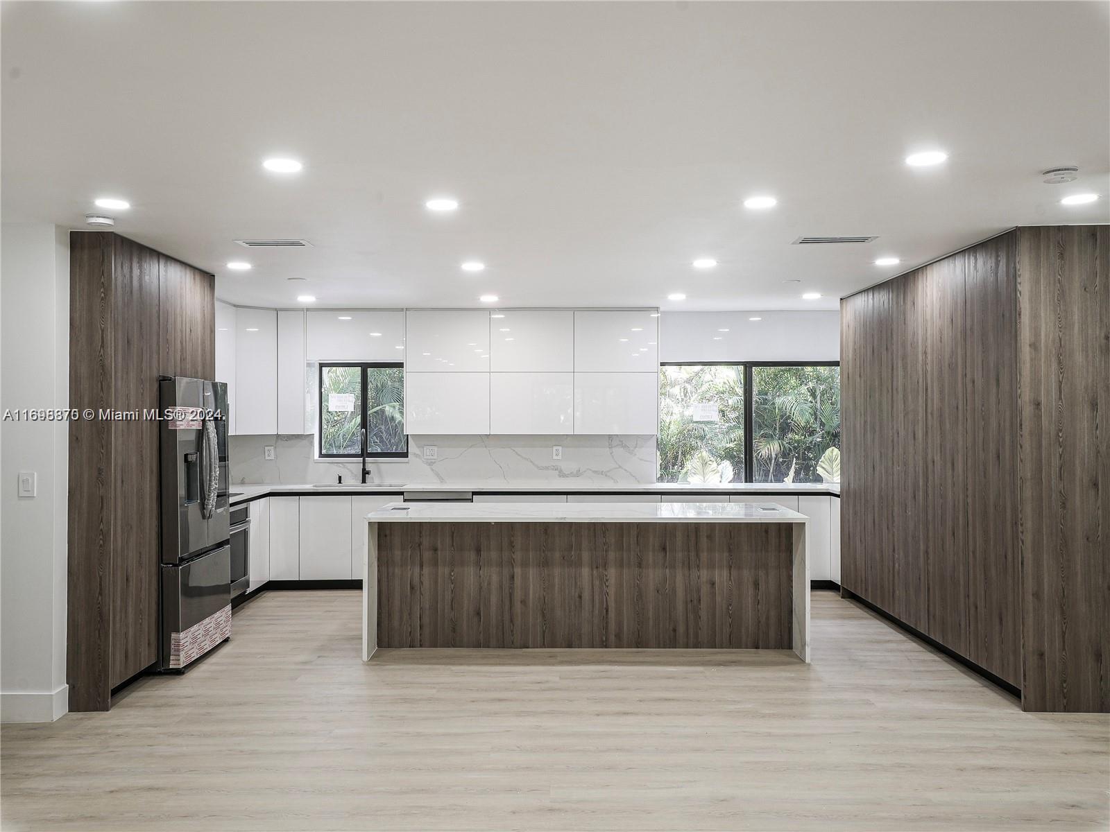 a large kitchen with stainless steel appliances granite countertop a refrigerator and a sink