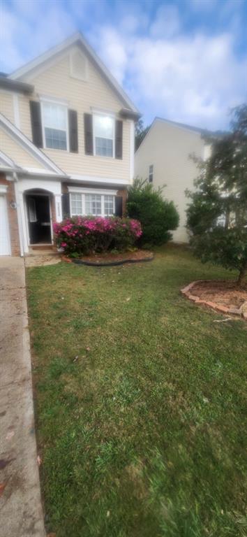 a front view of house with yard and trees in the background