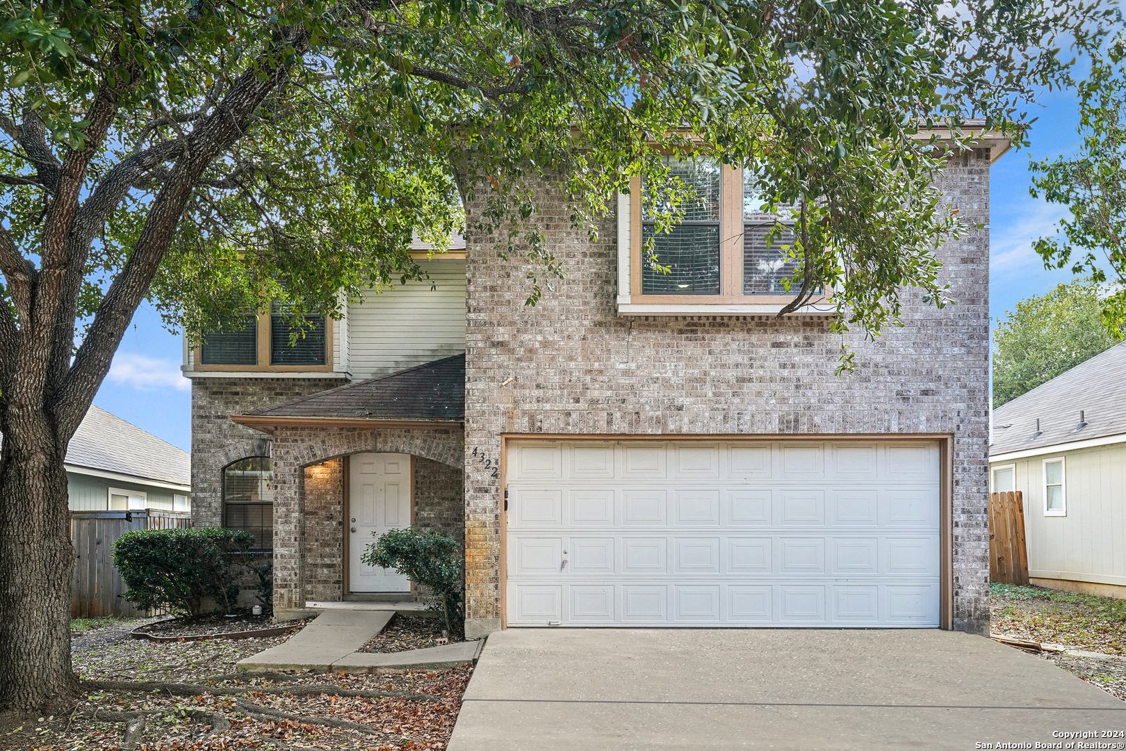 a front view of a house with a tree