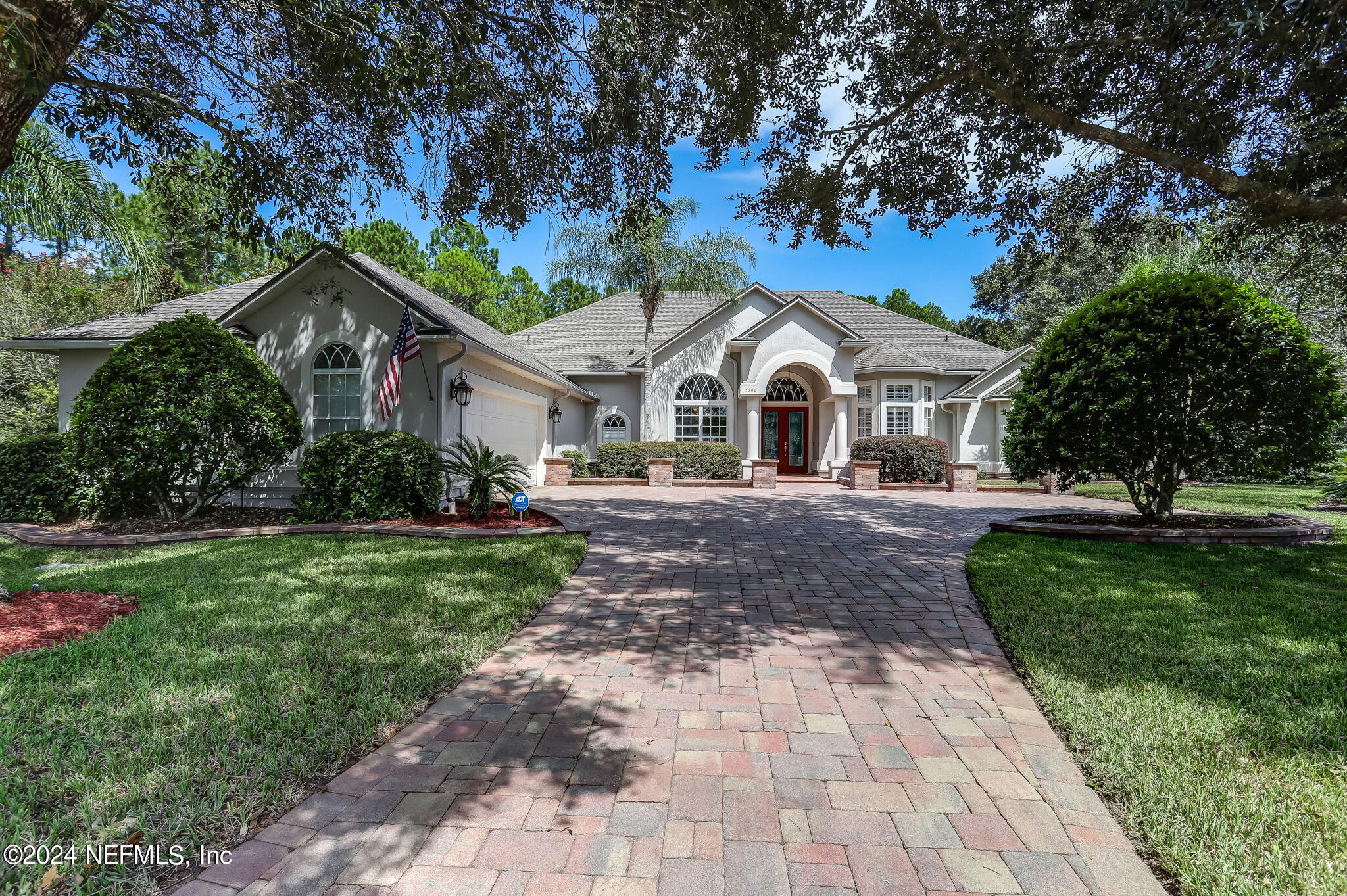 a front view of a house with a garden and trees