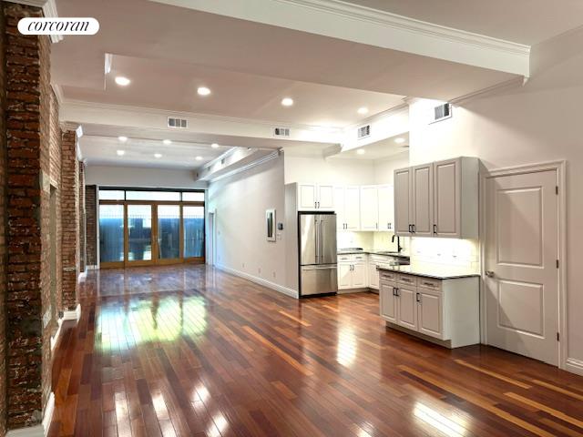 a kitchen with kitchen island wooden floors and refrigerator