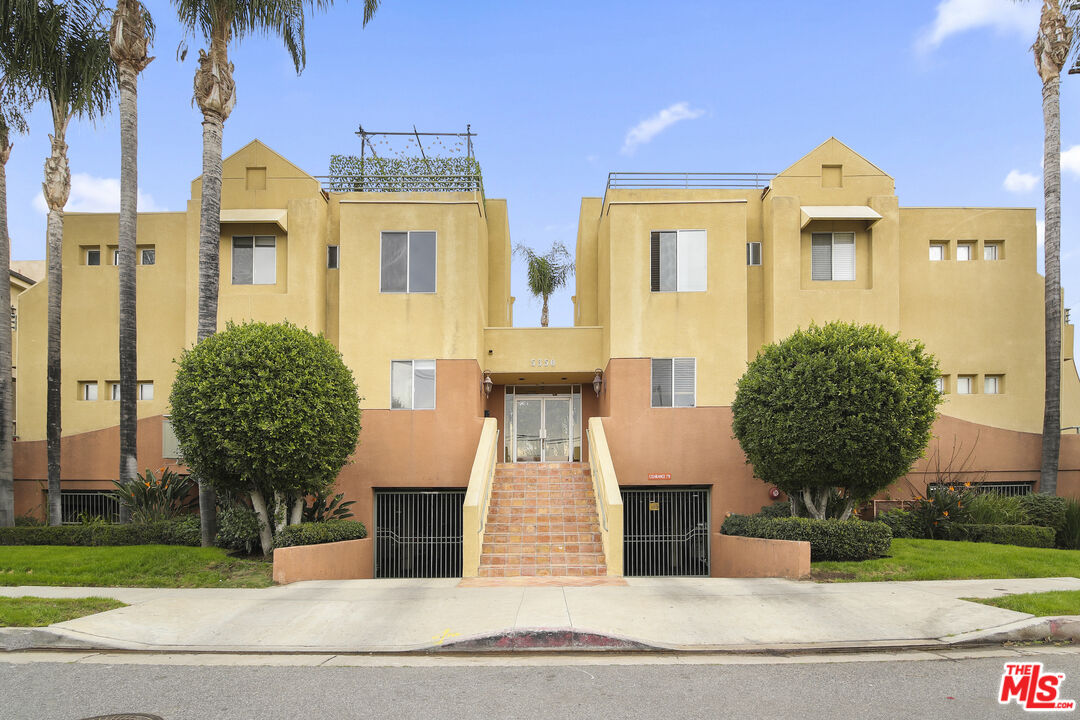 a front view of a residential apartment building with a yard and potted plants