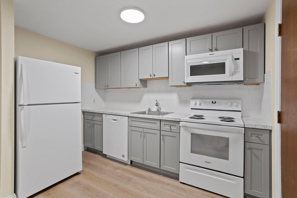 a kitchen with cabinets stainless steel appliances and wooden floor