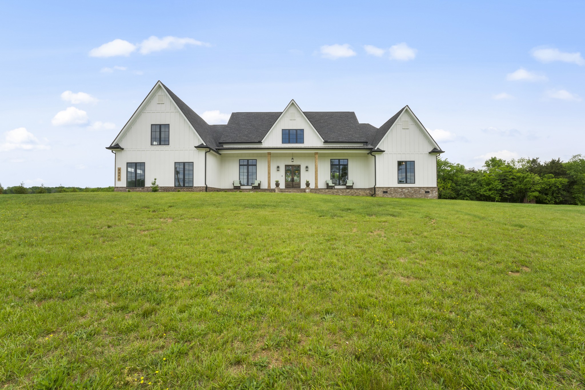 a view of a house with a big yard and large trees