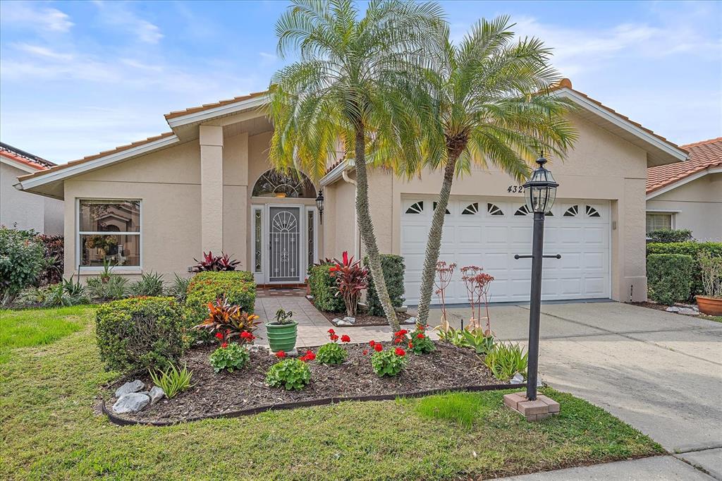 a front view of yellow house with a yard and potted plants