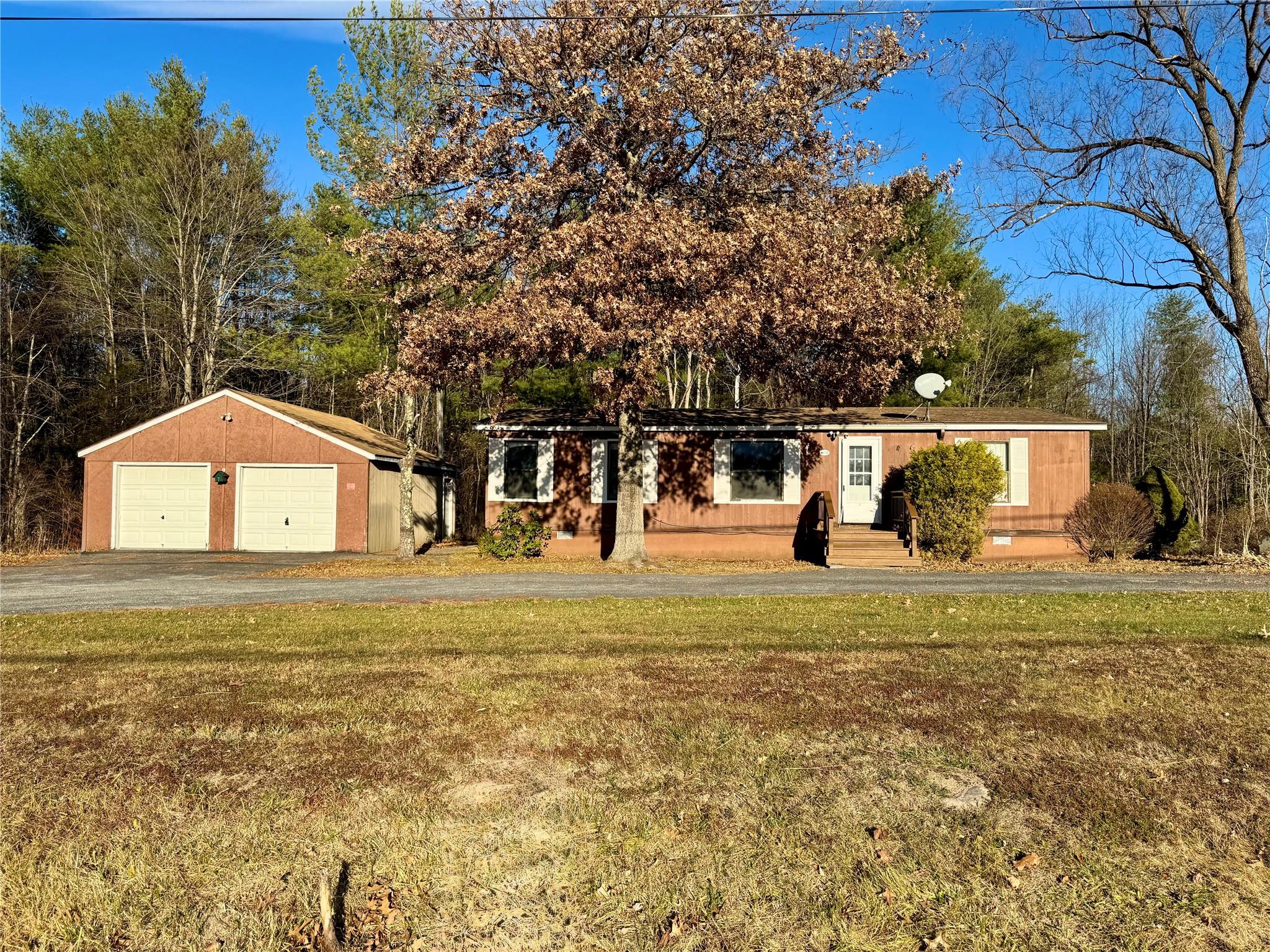 View of front of home with an outbuilding, a front yard, and a garage