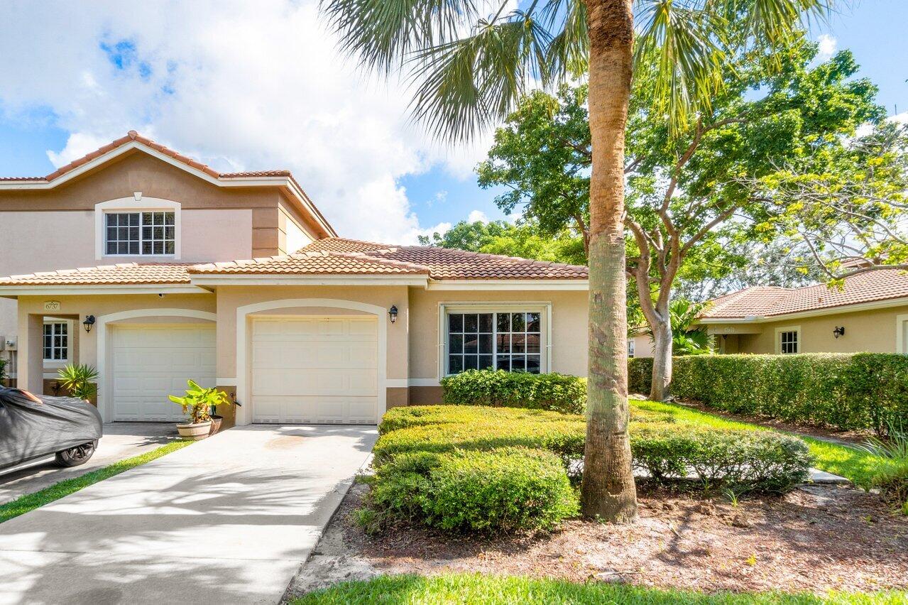 a view of a house with a small yard plants and palm trees