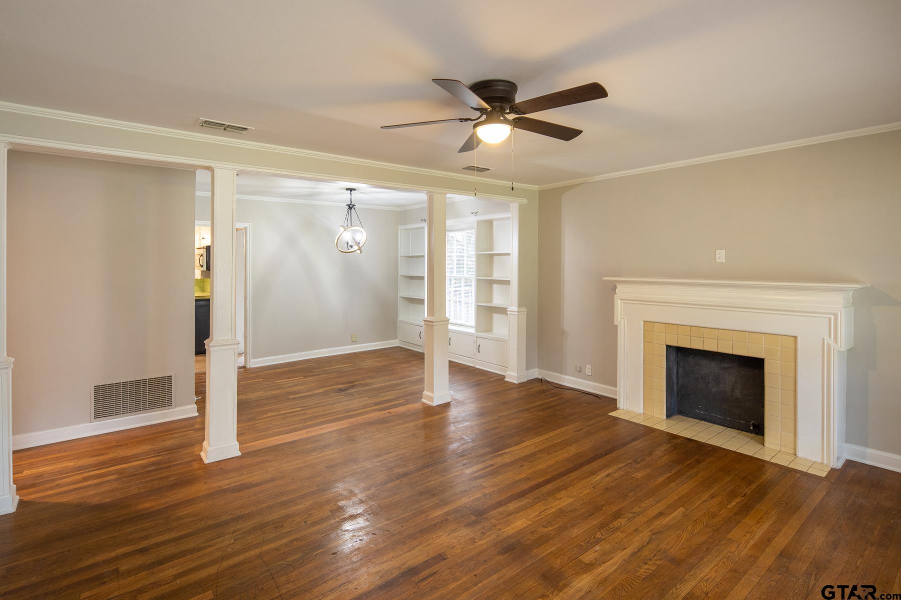 a view of an empty room with wooden floor fireplace and a window