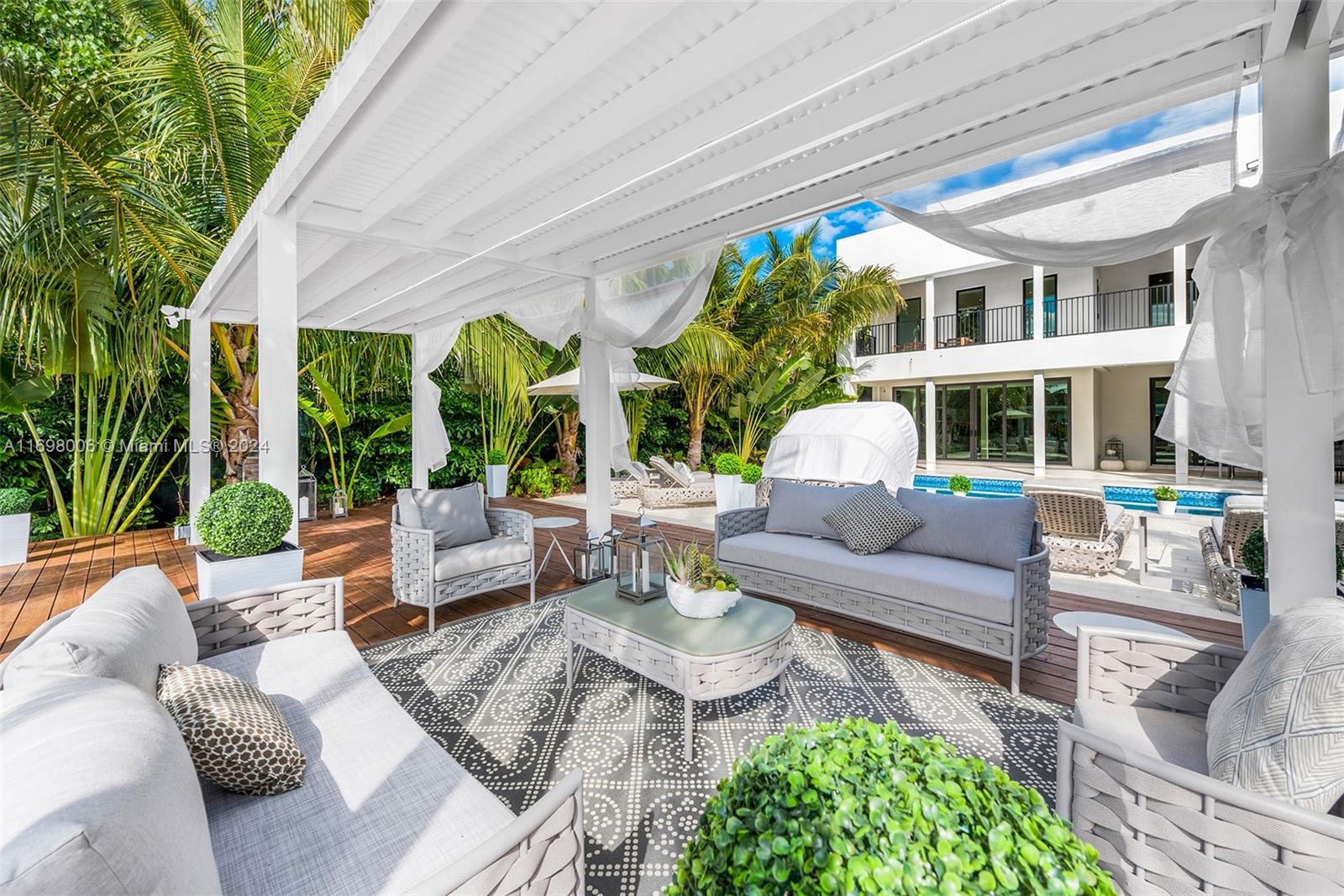 a view of a patio with couches table and chairs potted plants and large tree