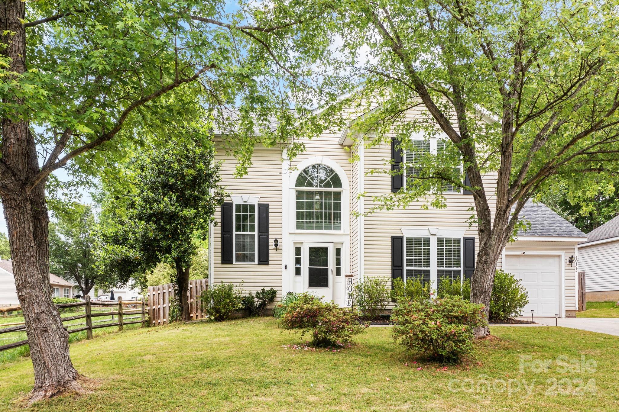 a front view of a house with a garden and trees