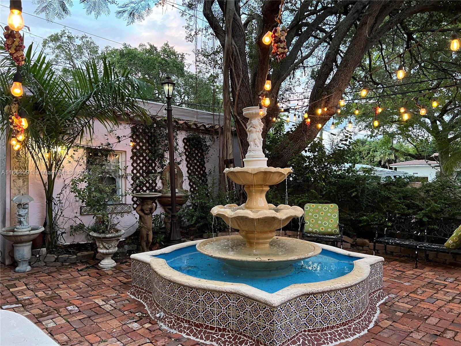 a view of a fire pit with table and chairs potted plants and large tree