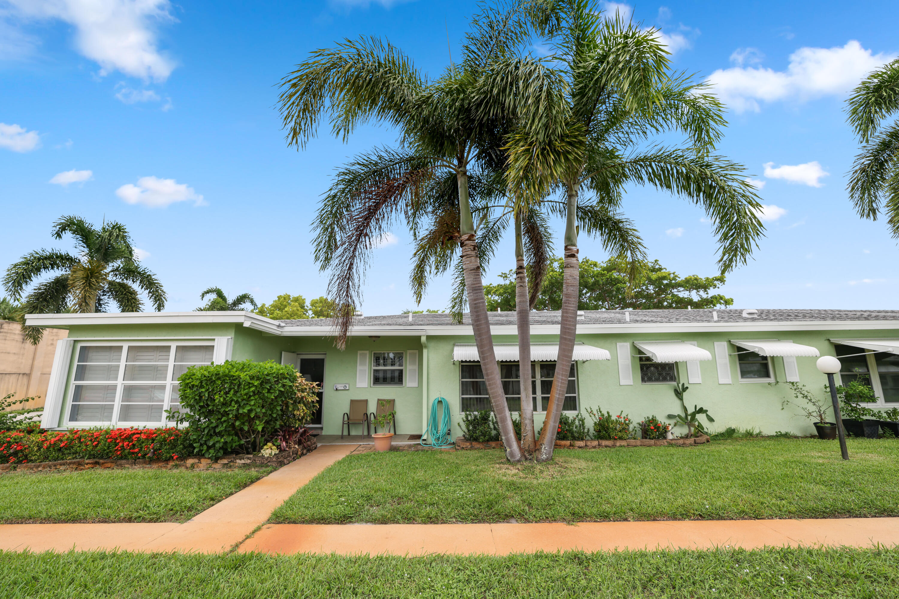 a view of a white house with a yard and palm trees