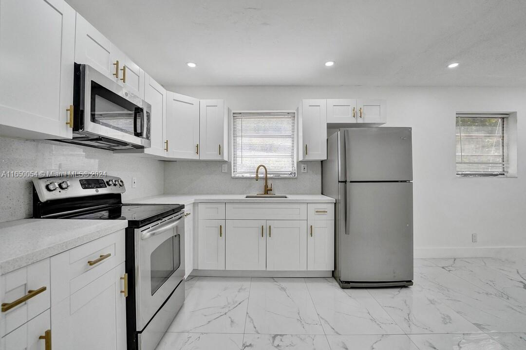 a kitchen with stainless steel appliances granite countertop a refrigerator sink and stove