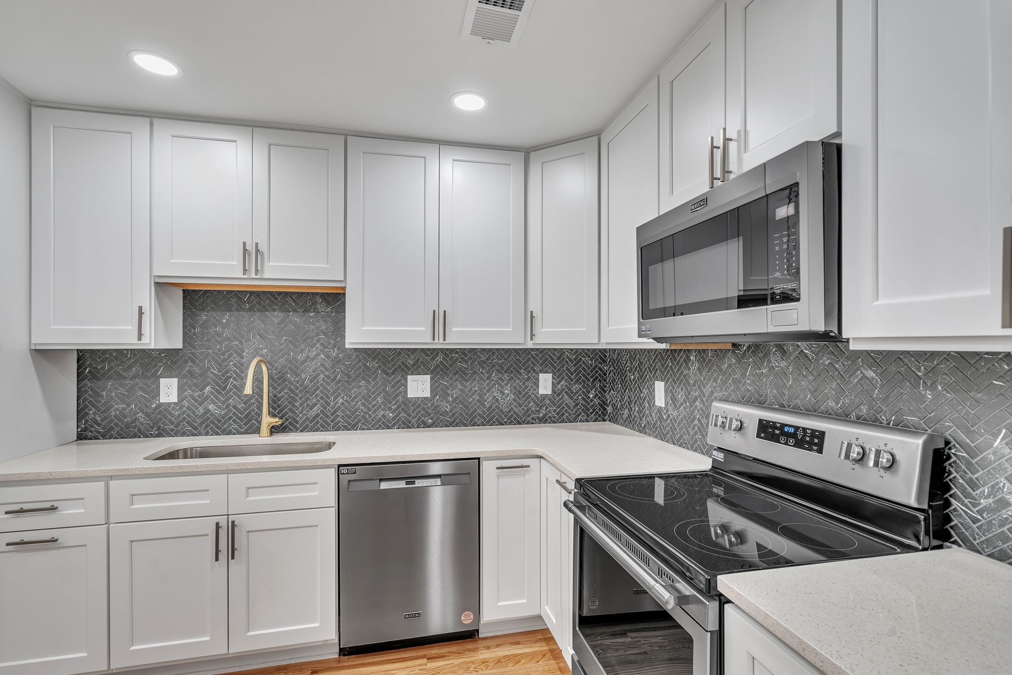 a kitchen with granite countertop white cabinets and stainless steel appliances