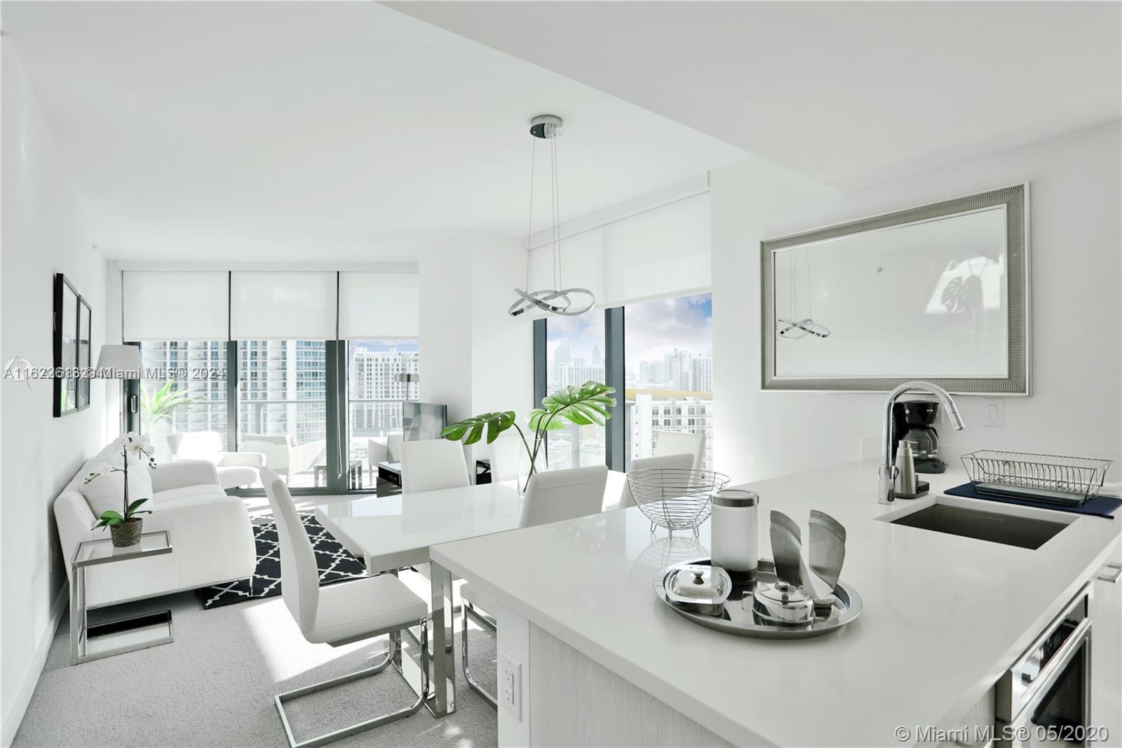 a living room with furniture kitchen view and large windows