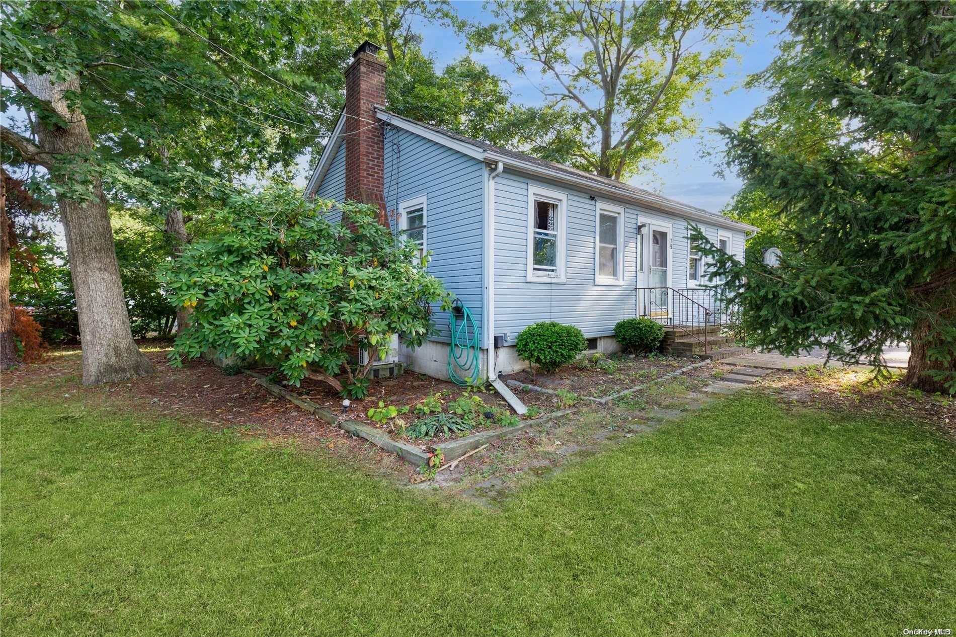 a backyard of a house with table and chairs plants and large tree