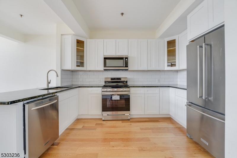 a kitchen with granite countertop a refrigerator and a stove top oven