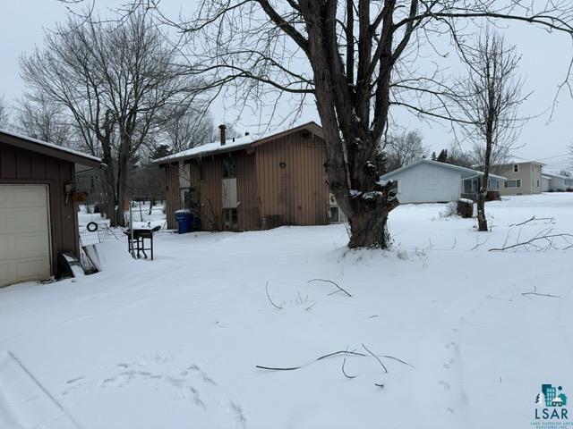 Yard covered in snow featuring a garage