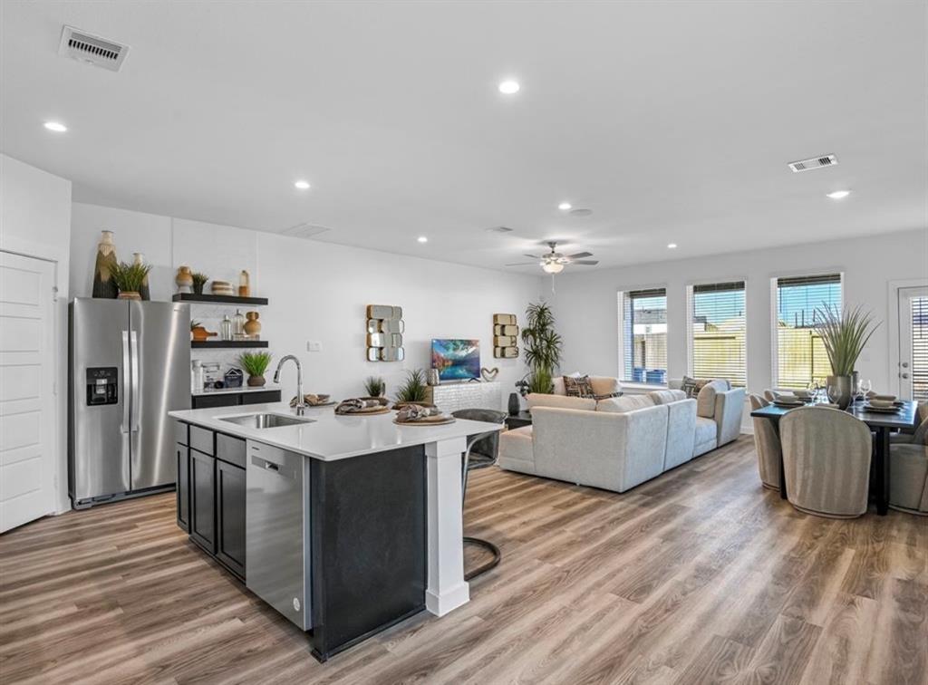 a large living room with stainless steel appliances granite countertop furniture wooden floor and a view of kitchen