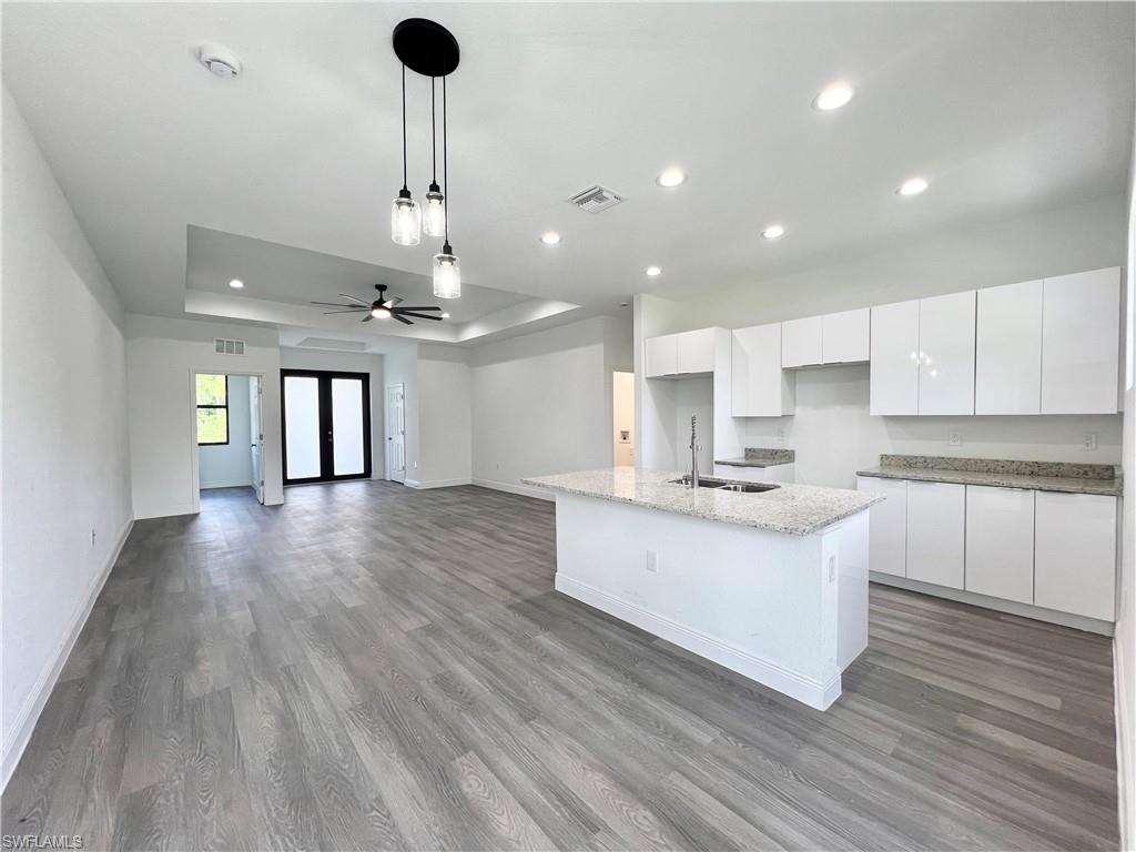 a kitchen with kitchen island stainless steel appliances granite countertop a sink a stove and a wooden floors