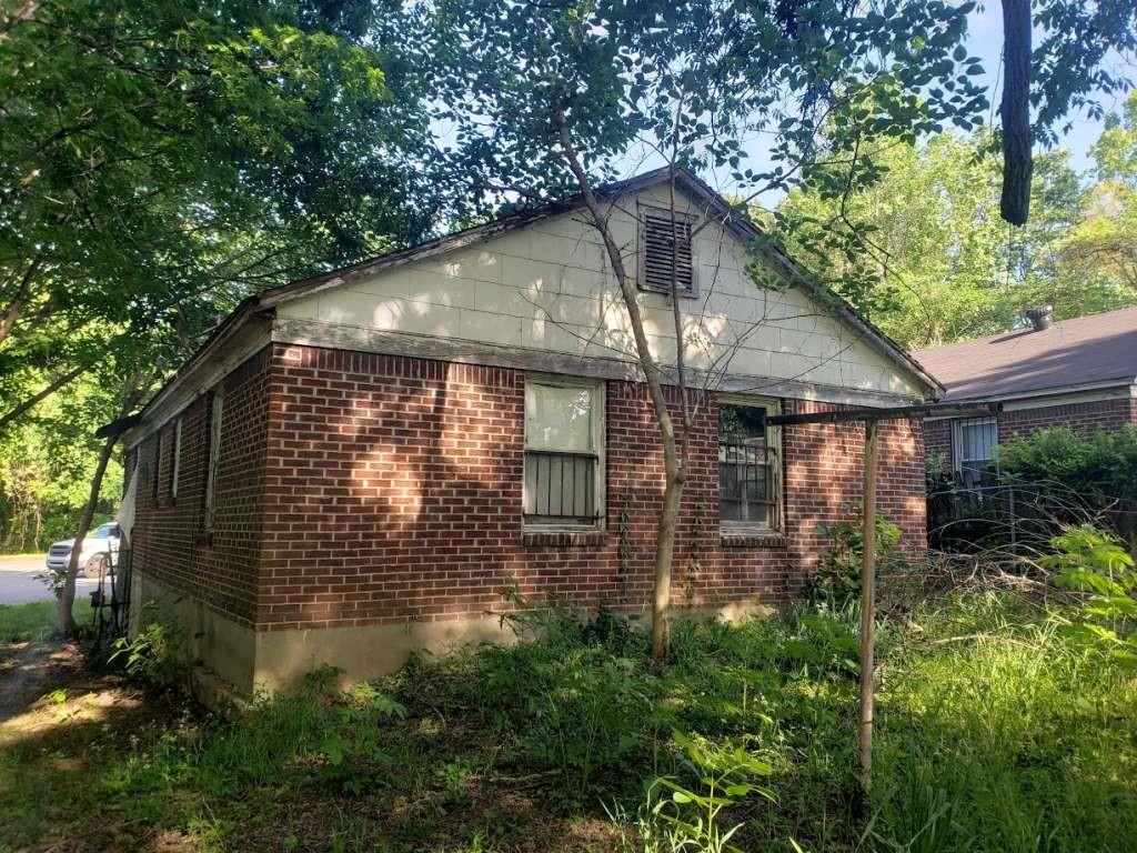 a backyard of a house with plants and tree next to a yard