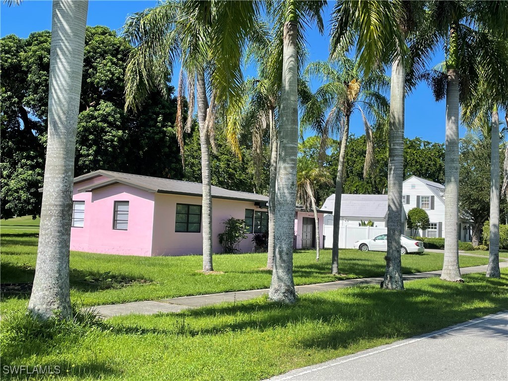 a front view of a house with a yard and palm trees