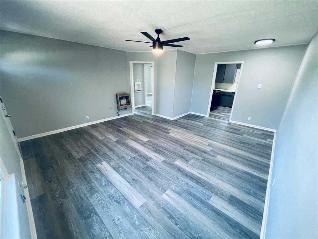 an empty room with wooden floor and ceiling fan