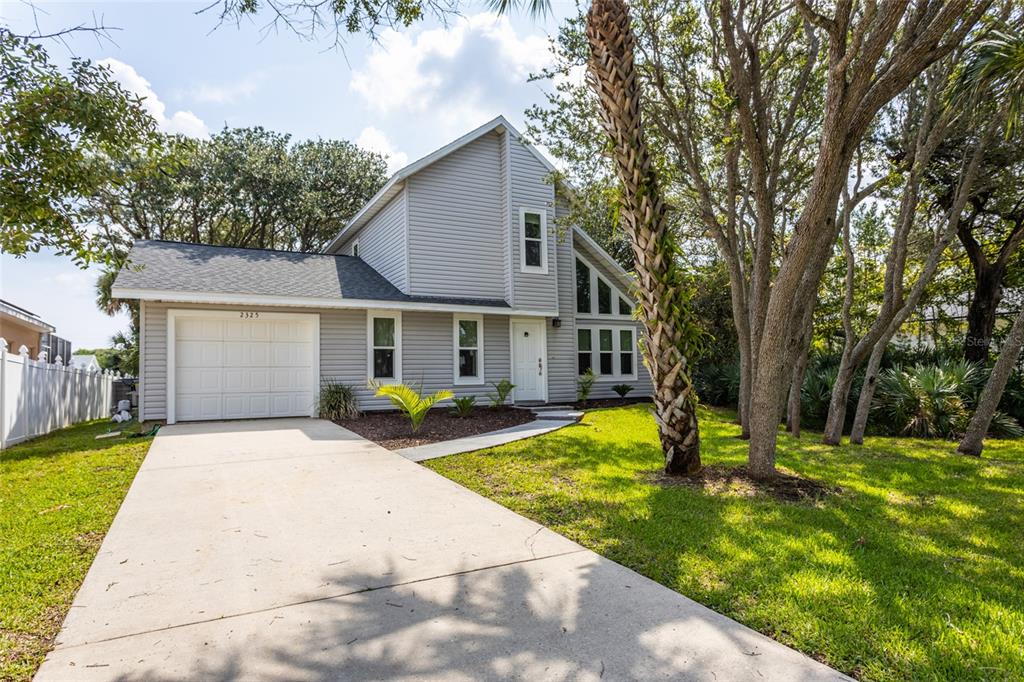 a front view of house with yard and trees in the background