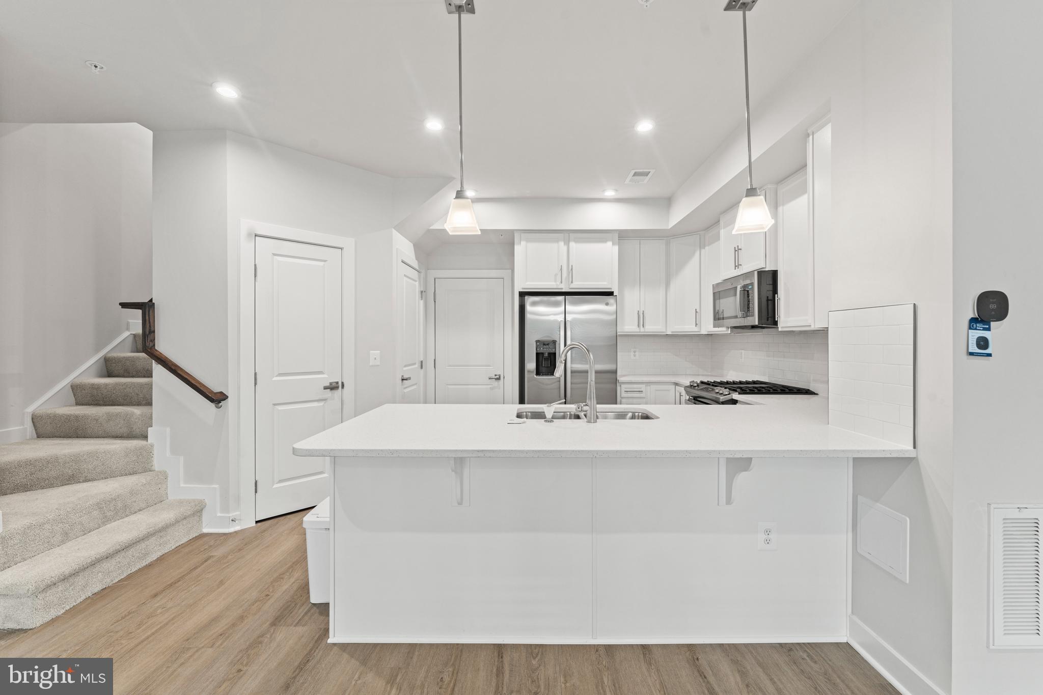 a large white kitchen with kitchen island a sink a stove and a refrigerator