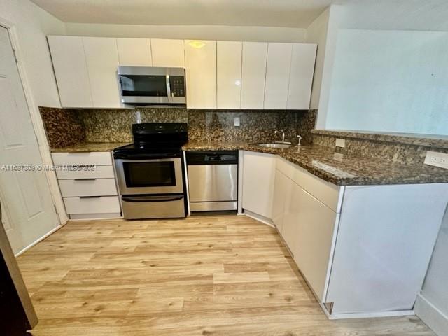 a kitchen with granite countertop a stove top oven a sink a counter space and cabinets