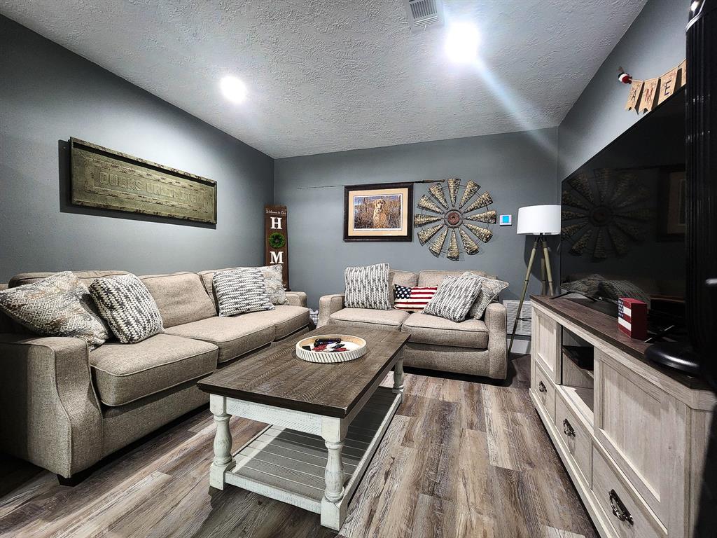 a living room with furniture a flat screen tv and kitchen view