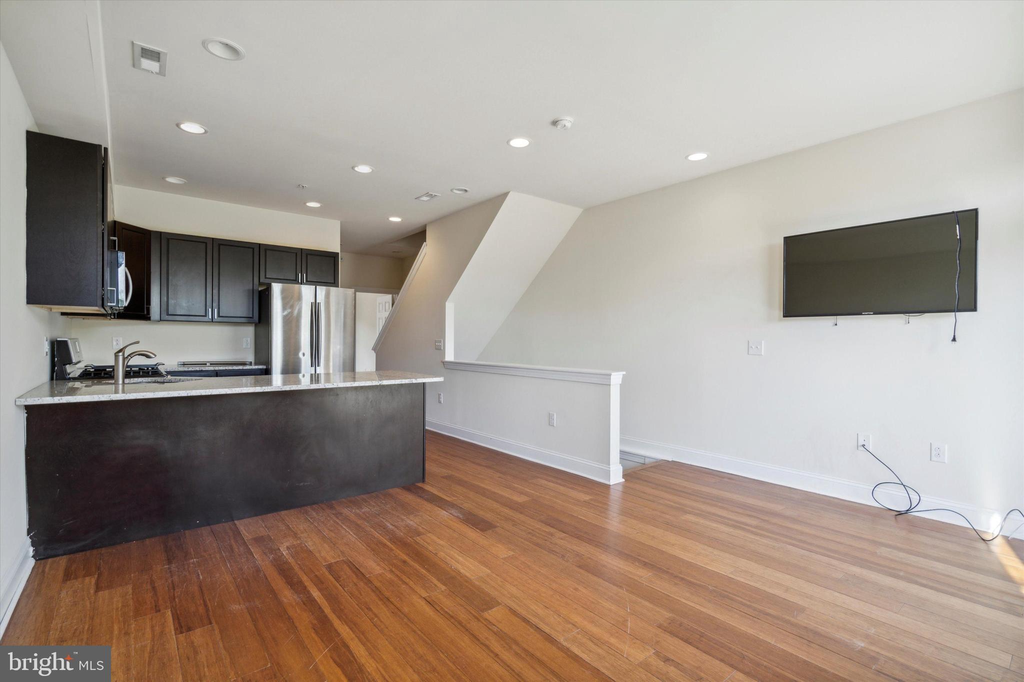 a view of kitchen living space with stainless steel appliances wooden floor and view living room