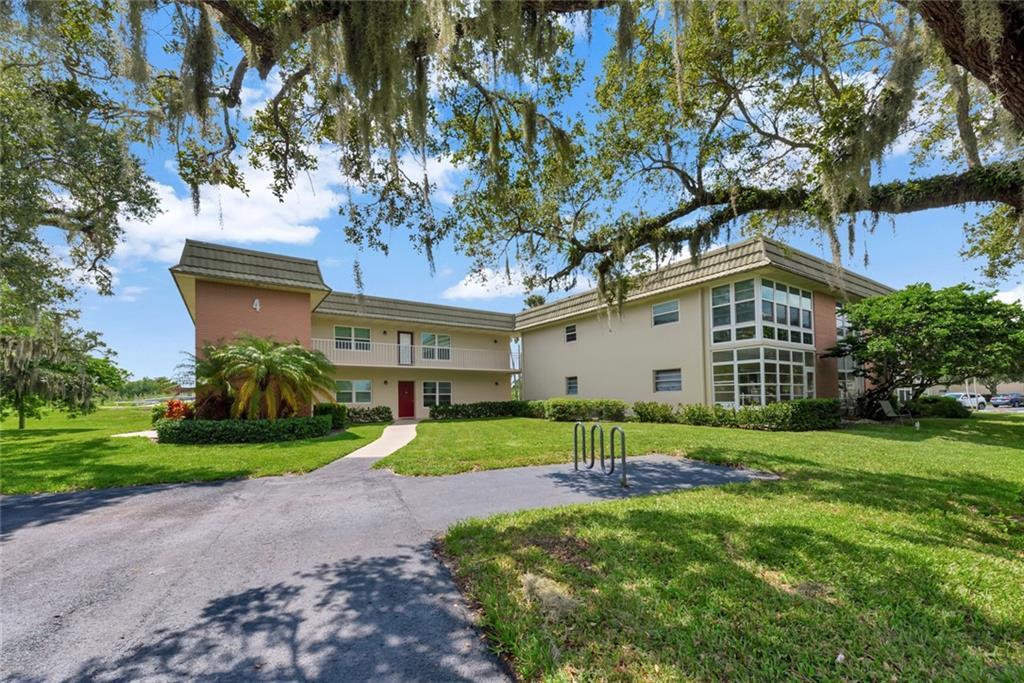 a view of house with a big yard plants and large trees