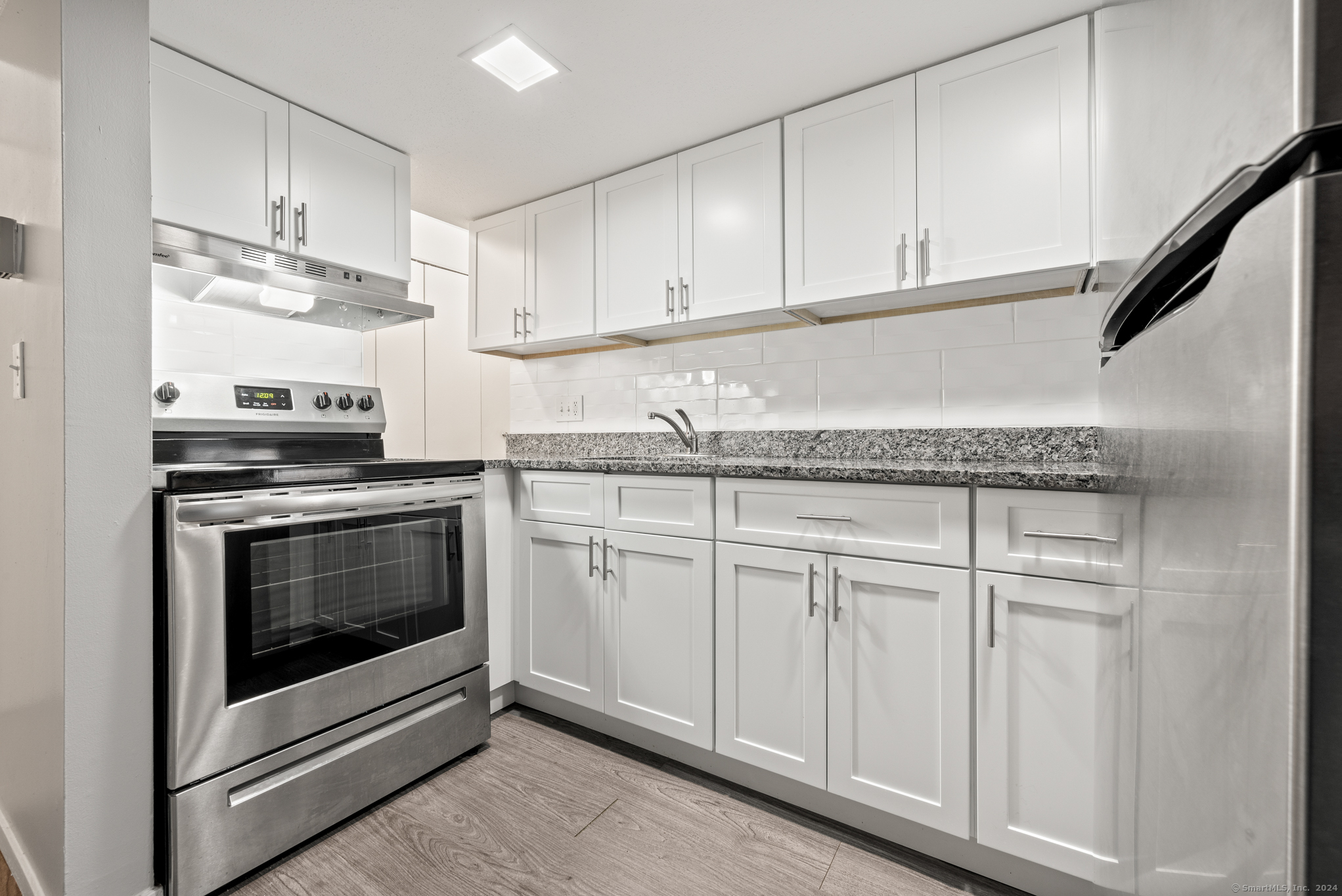 a kitchen with granite countertop white cabinets and white appliances