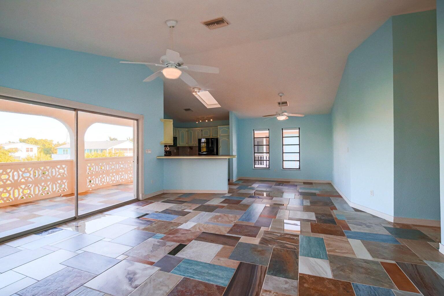 a view of an empty room with window and chandelier fan