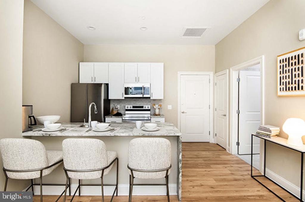 a kitchen with stainless steel appliances granite countertop a dining table chairs and a refrigerator