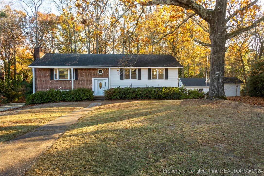 a view of a house with a yard and large trees