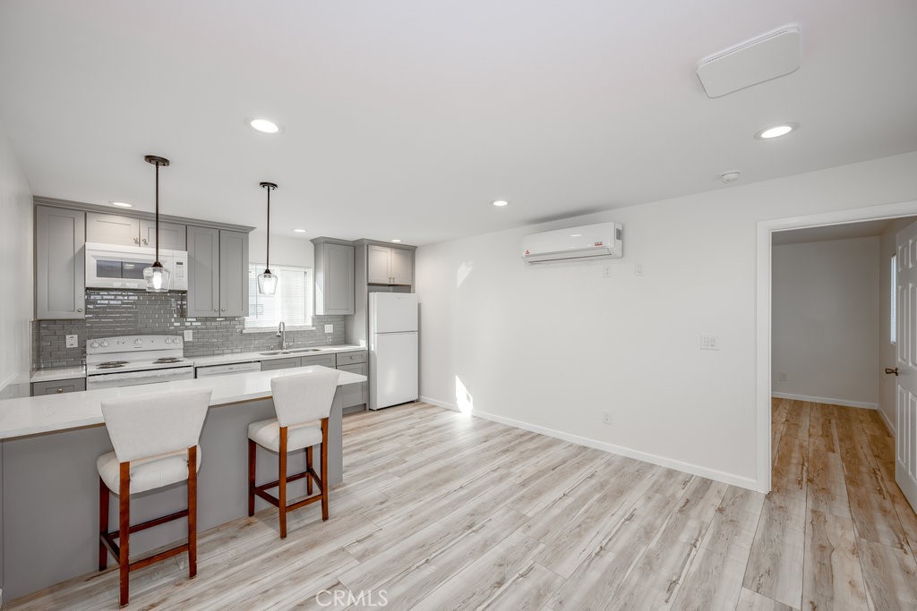 a kitchen with kitchen island wooden floors white appliances and cabinets