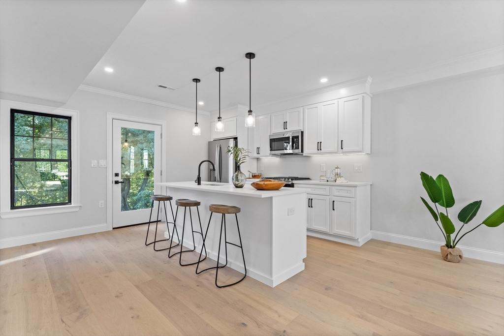 a kitchen with white cabinets and wooden floor