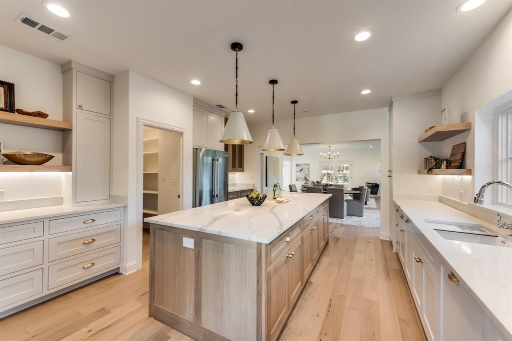 a large kitchen with kitchen island a stove a sink a refrigerator and a cabinets